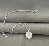 Silver necklace with a pendant on a gray surface
