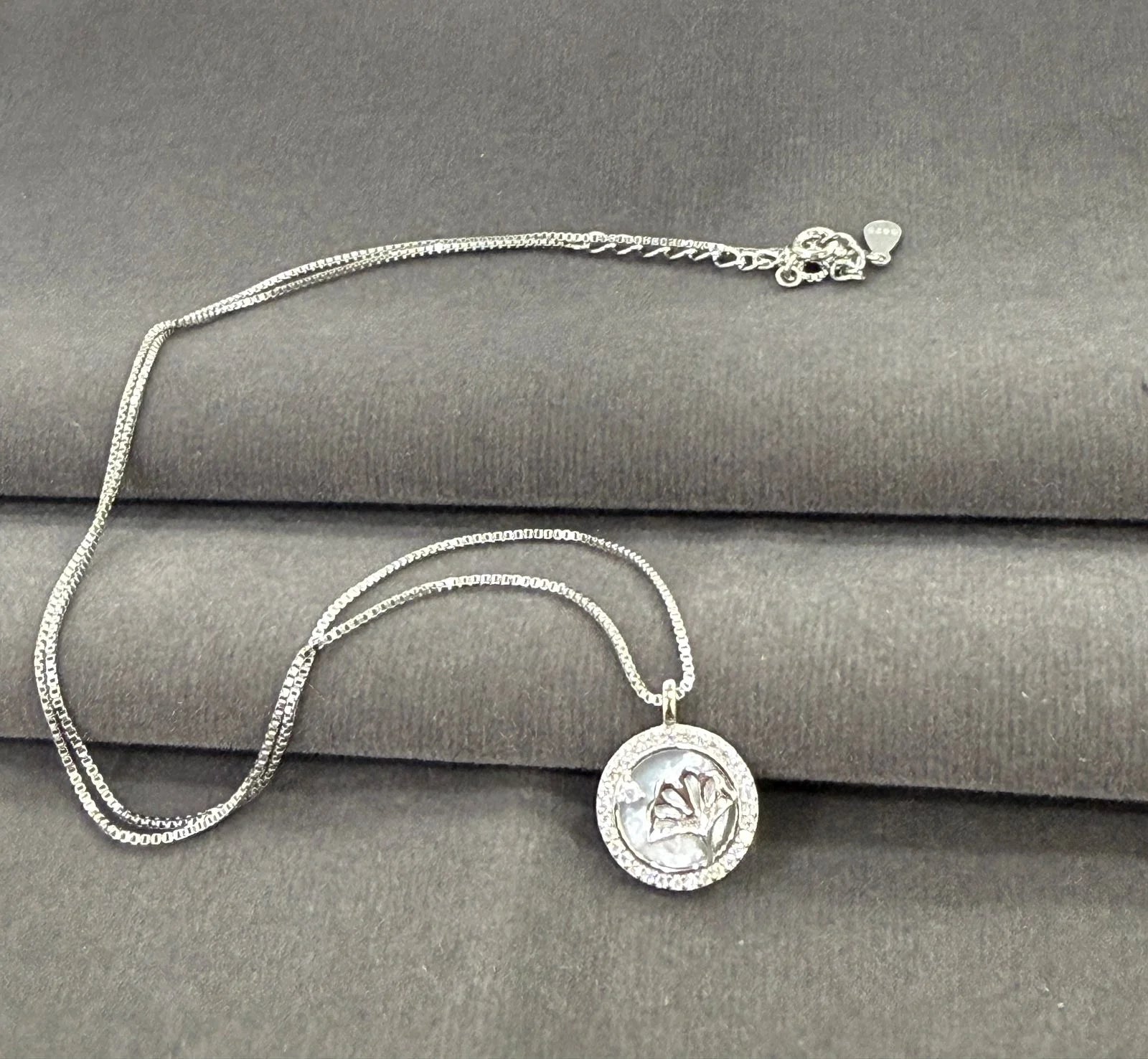 Silver necklace with a pendant on a gray surface