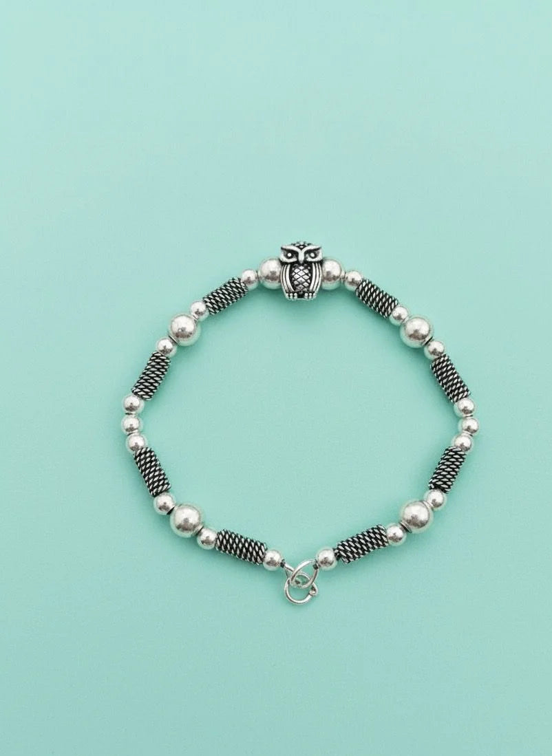 Bracelet with owl charm on a light blue background