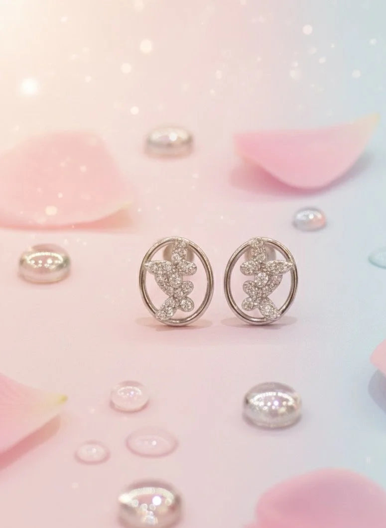 Pair of silver earrings with gemstones on a soft pink and blue background