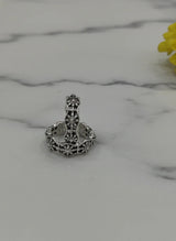 Silver toe ring with intricate design on a marble surface with a yellow flower.