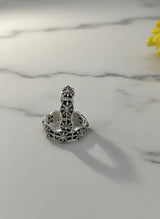 Silver toe ring with intricate design on a marble surface with a yellow flower.
