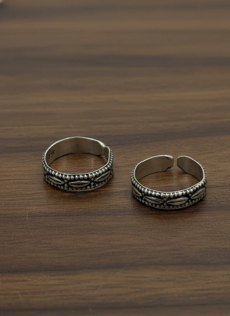 Two silver toe rings on a wooden surface