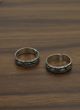Two silver toe rings on a wooden surface
