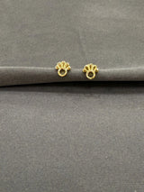 Two gold earrings on a gray surface