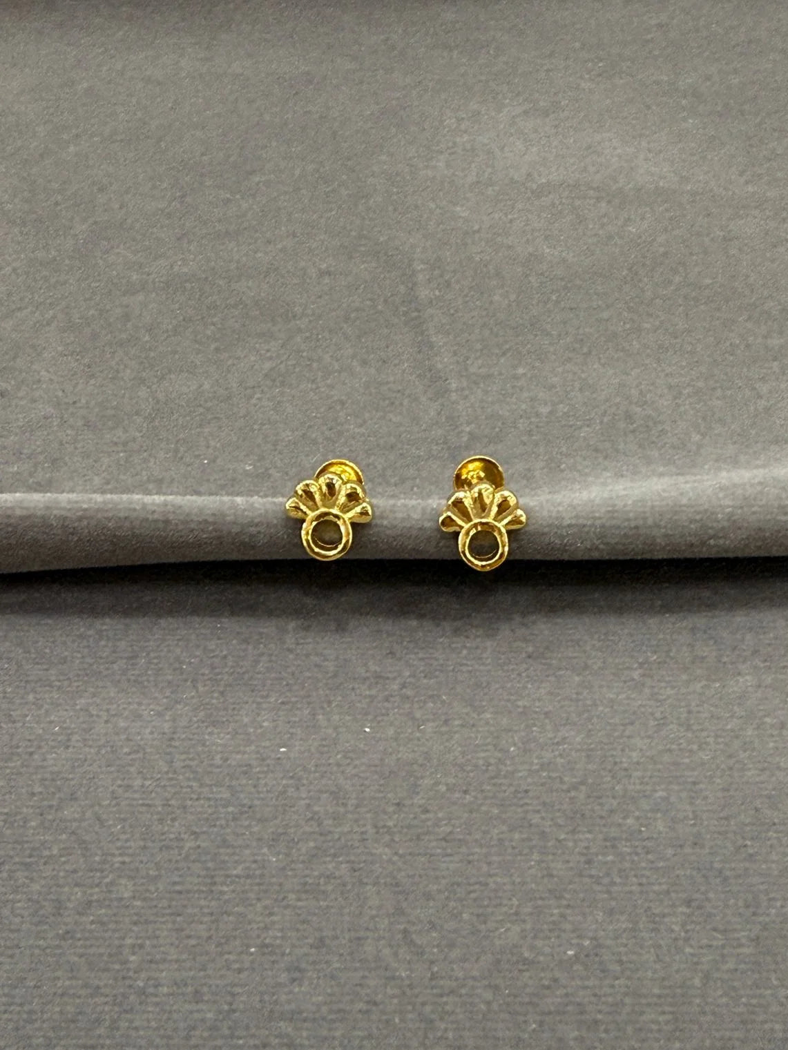 Gold earrings on a gray surface