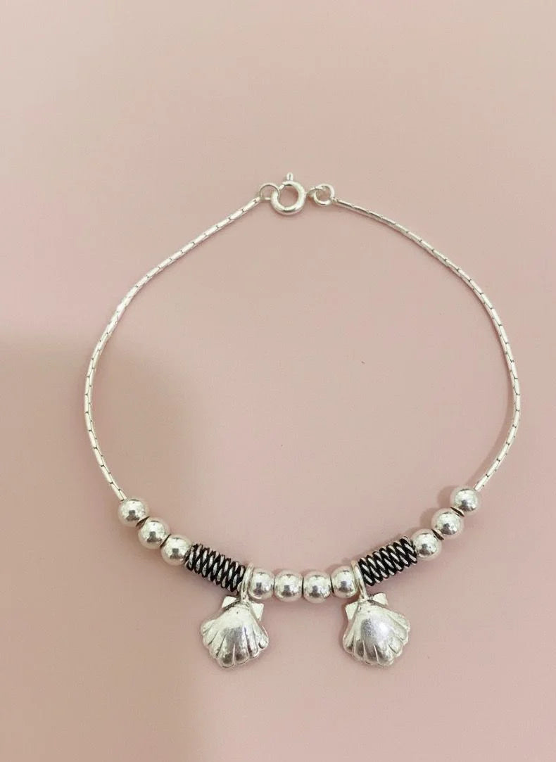 Silver bracelet with shell hangings on a pink background