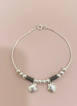 Silver bracelet with shell hangings on a pink background