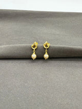 Gold earrings with pearl beads on a gray surface
