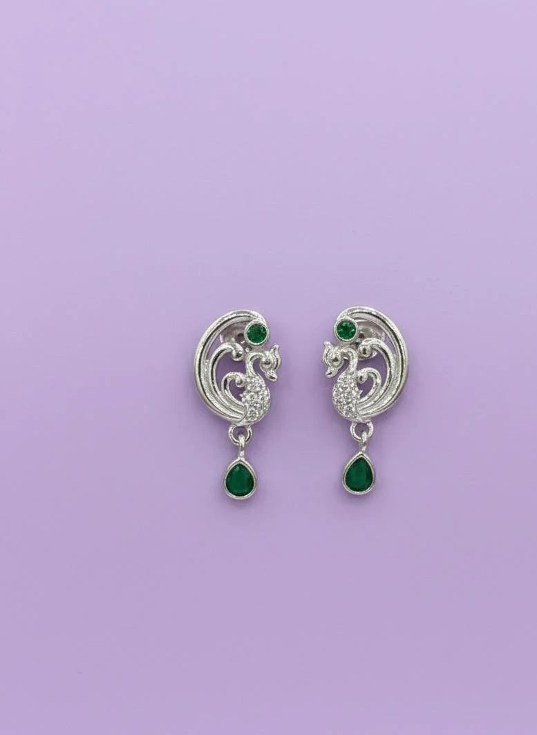 Pair of silver earrings with green gemstones on a purple background