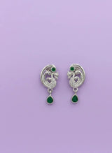 Pair of silver earrings with green gemstones on a purple background