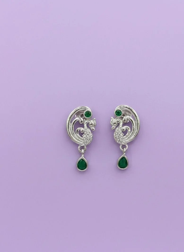 Pair of silver earrings with green gemstones on a purple background