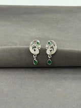 Silver earrings with green gemstones on a gray surface