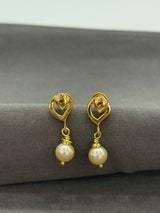 Gold earrings with pearl drops on a gray surface