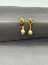 Gold earrings with pearl drops on a gray surface