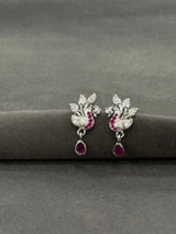 Pair of silver earrings with red gemstones on a gray surface