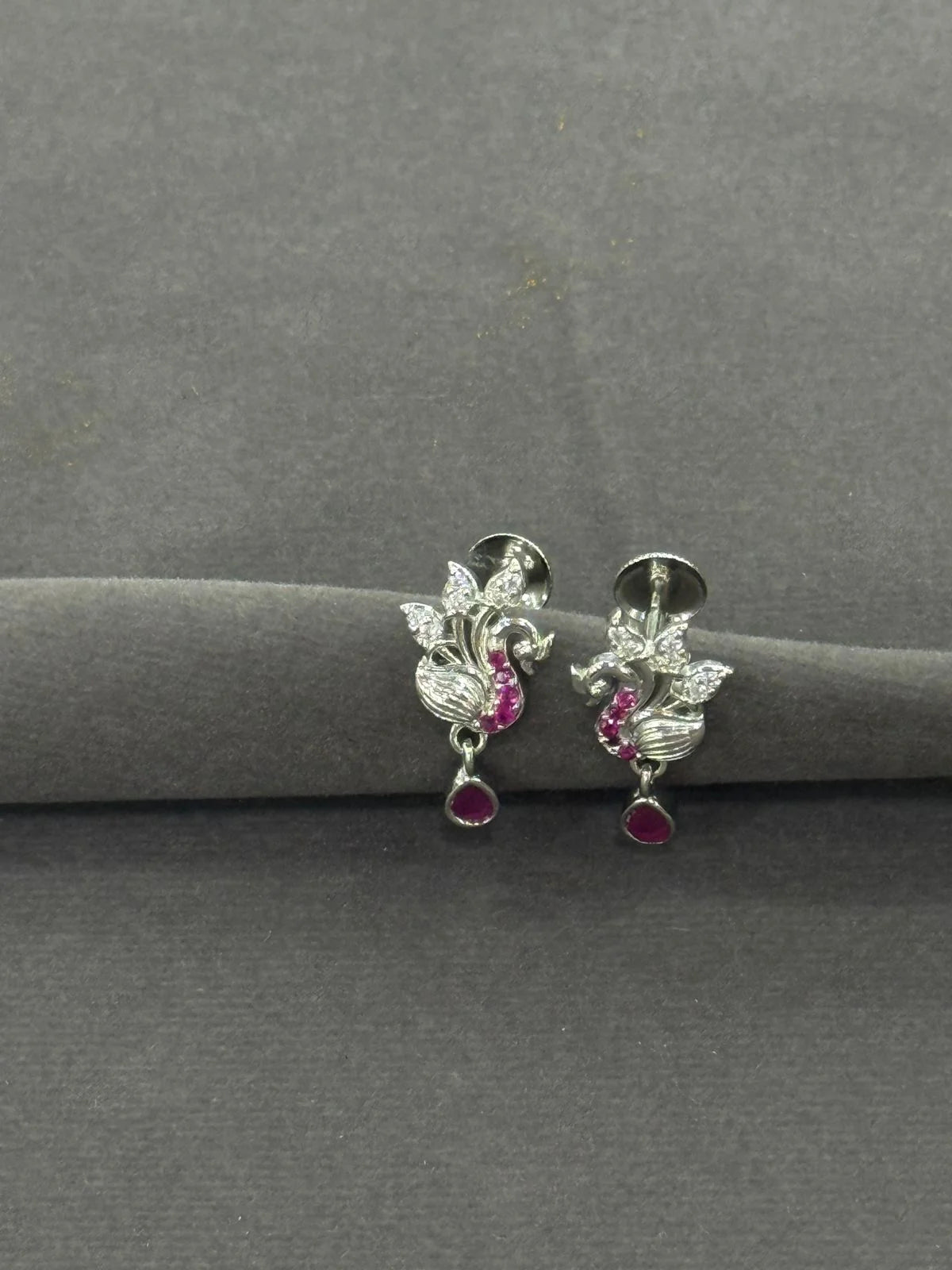 Silver earrings with gemstones on a gray surface