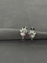 Silver earrings with gemstones on a gray surface