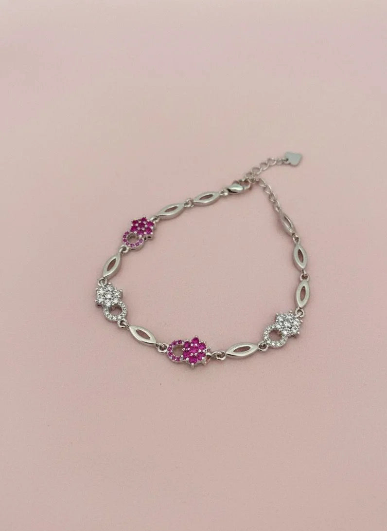 Silver bracelet with pink gemstones on a pink background