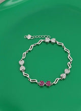 Silver bracelet with pink flowers on a green background