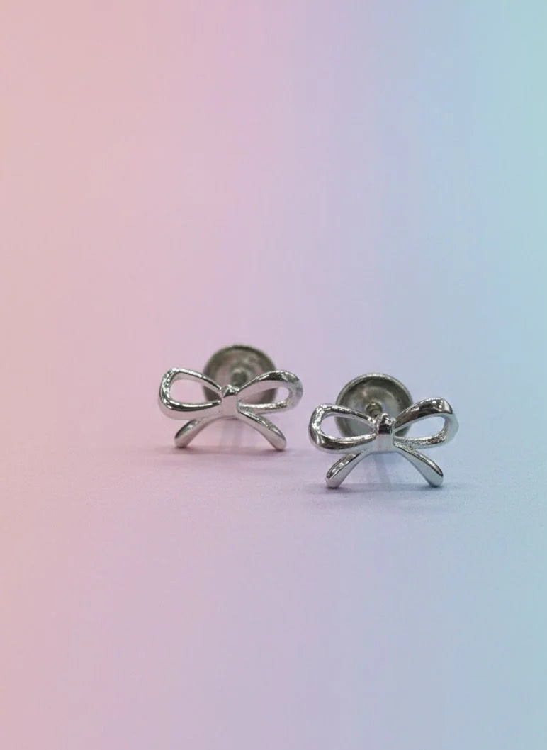 Silver bow-shaped earrings on a gradient background
