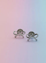Silver bow-shaped earrings on a gradient background