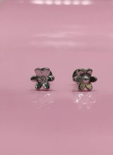 Flower-shaped earrings on a pink background