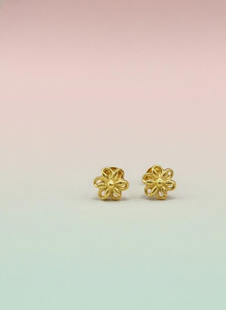 Pair of gold flower-shaped earrings on a pastel gradient background