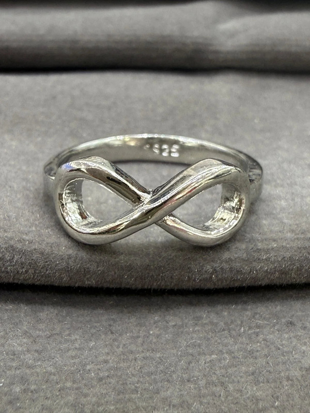 Silver infinity ring on a gray fabric background