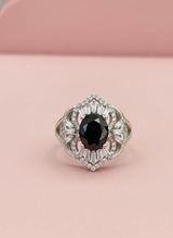 Elegant ring with a black gemstone on a pink background