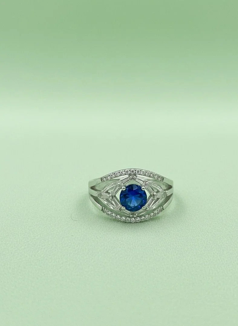 Silver ring with a blue gemstone on a light green background