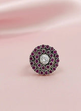 Decorative ring with purple gemstones on a pink fabric background