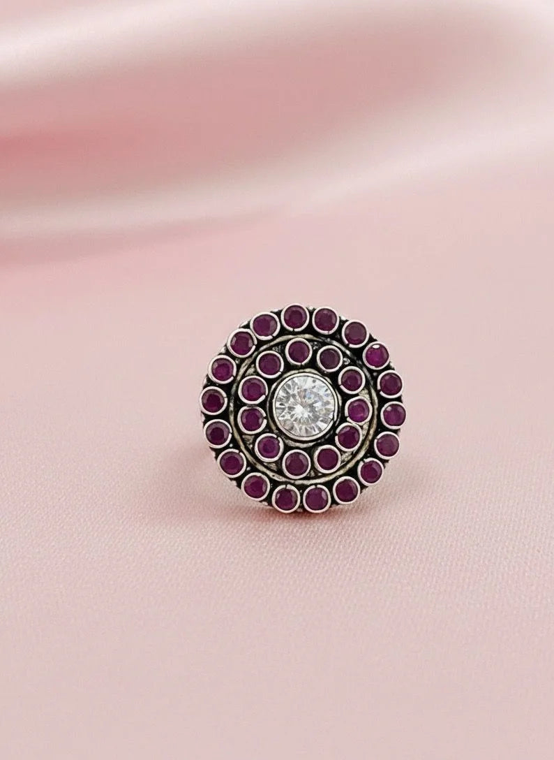 Decorative ring with purple gemstones on a pink fabric background