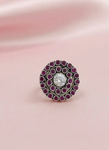 Decorative ring with purple gemstones on a pink fabric background