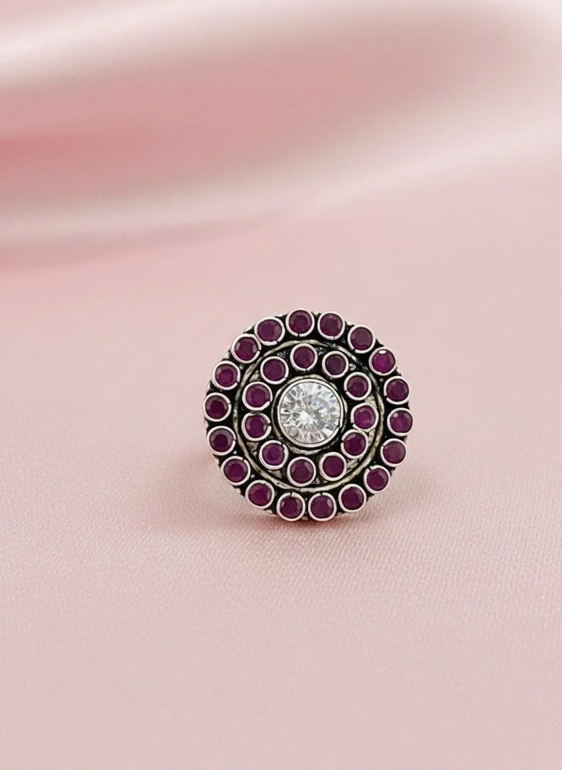 Decorative ring with purple gemstones on a pink fabric background