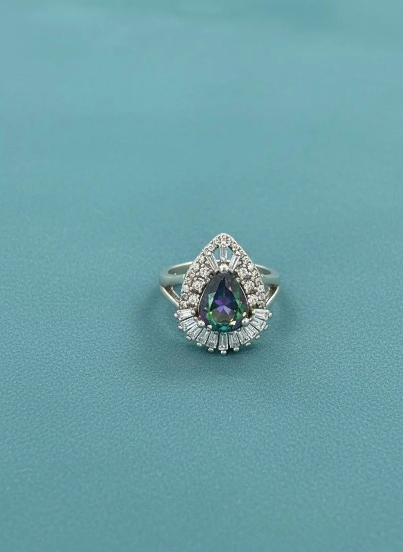Ring with a teardrop-shaped gemstone on a teal background
