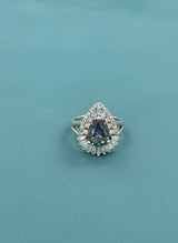 Ring with a teardrop-shaped gemstone on a teal background