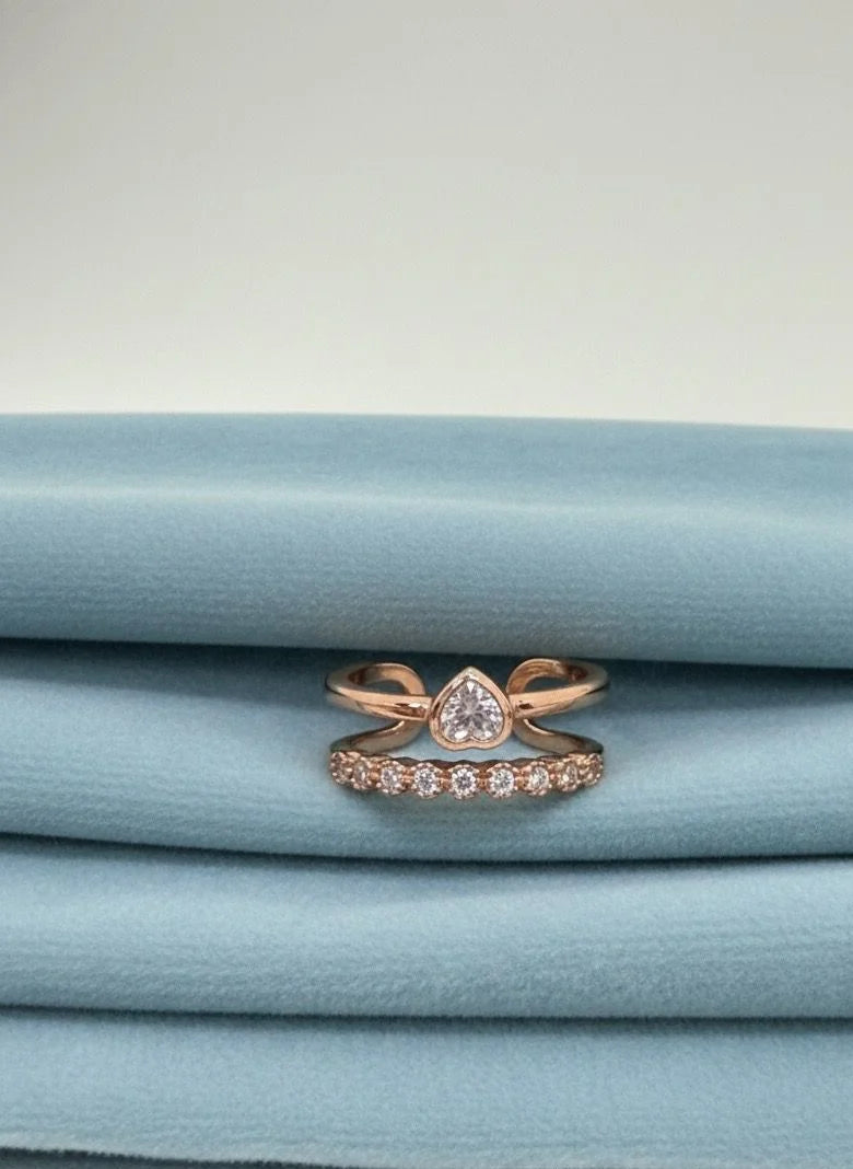 Rose gold ring with a pear-shaped center stone on a stack of blue fabric.