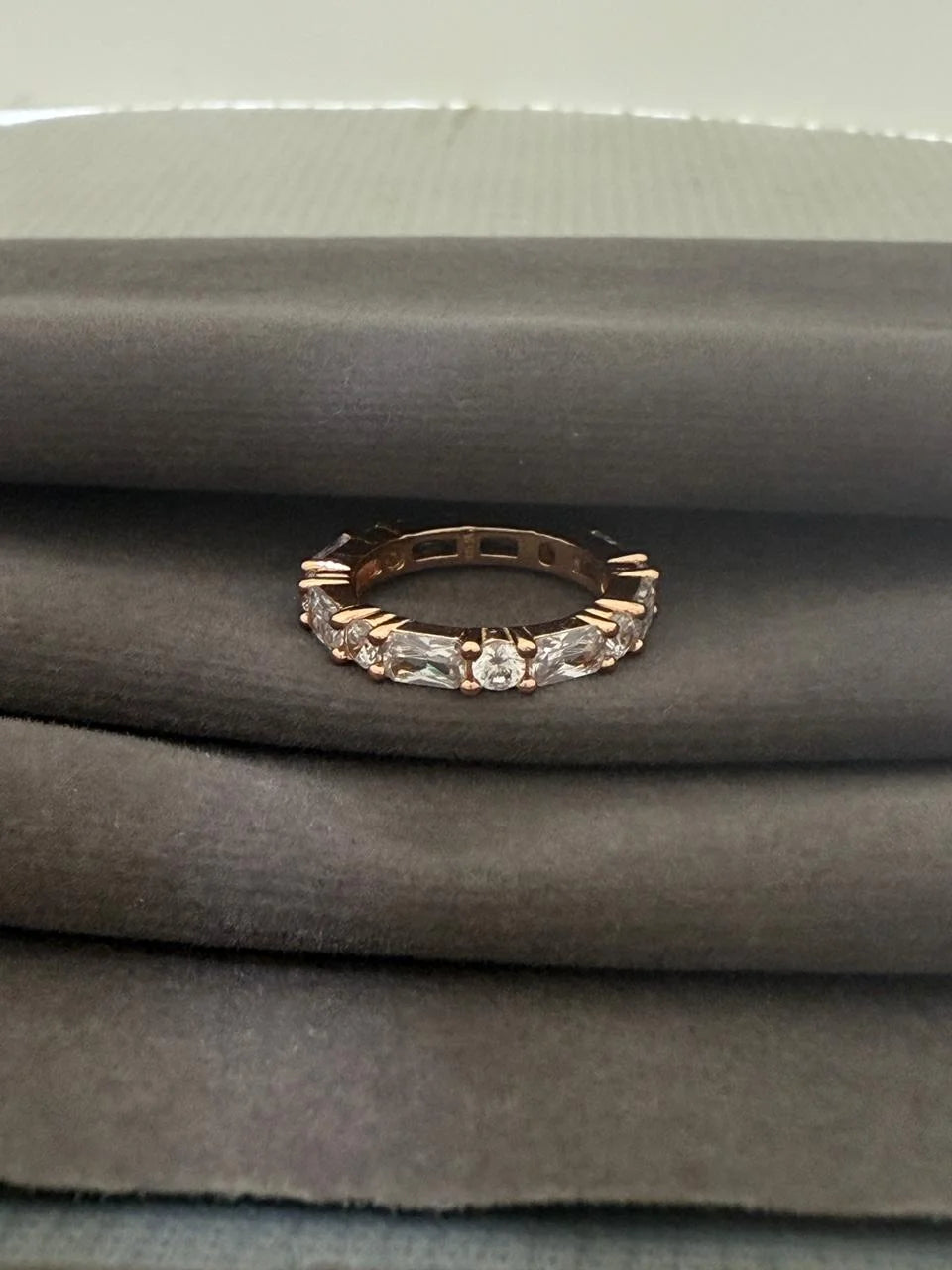 Rose gold ring with diamonds on a gray fabric background