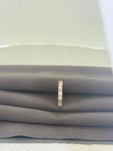 Rose gold ring with small diamonds on a stack of gray fabric