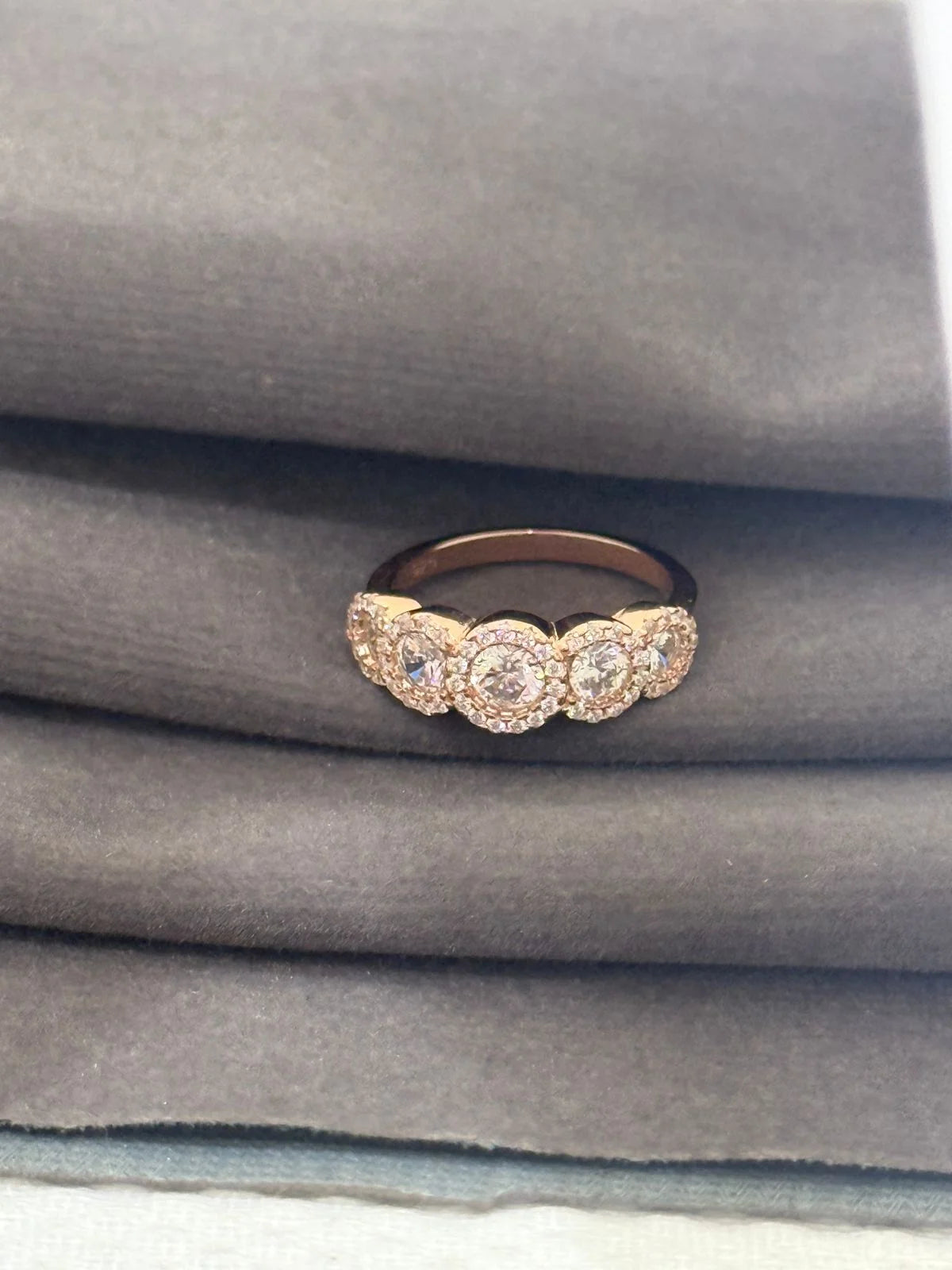 Rose gold ring with diamonds on a gray fabric background