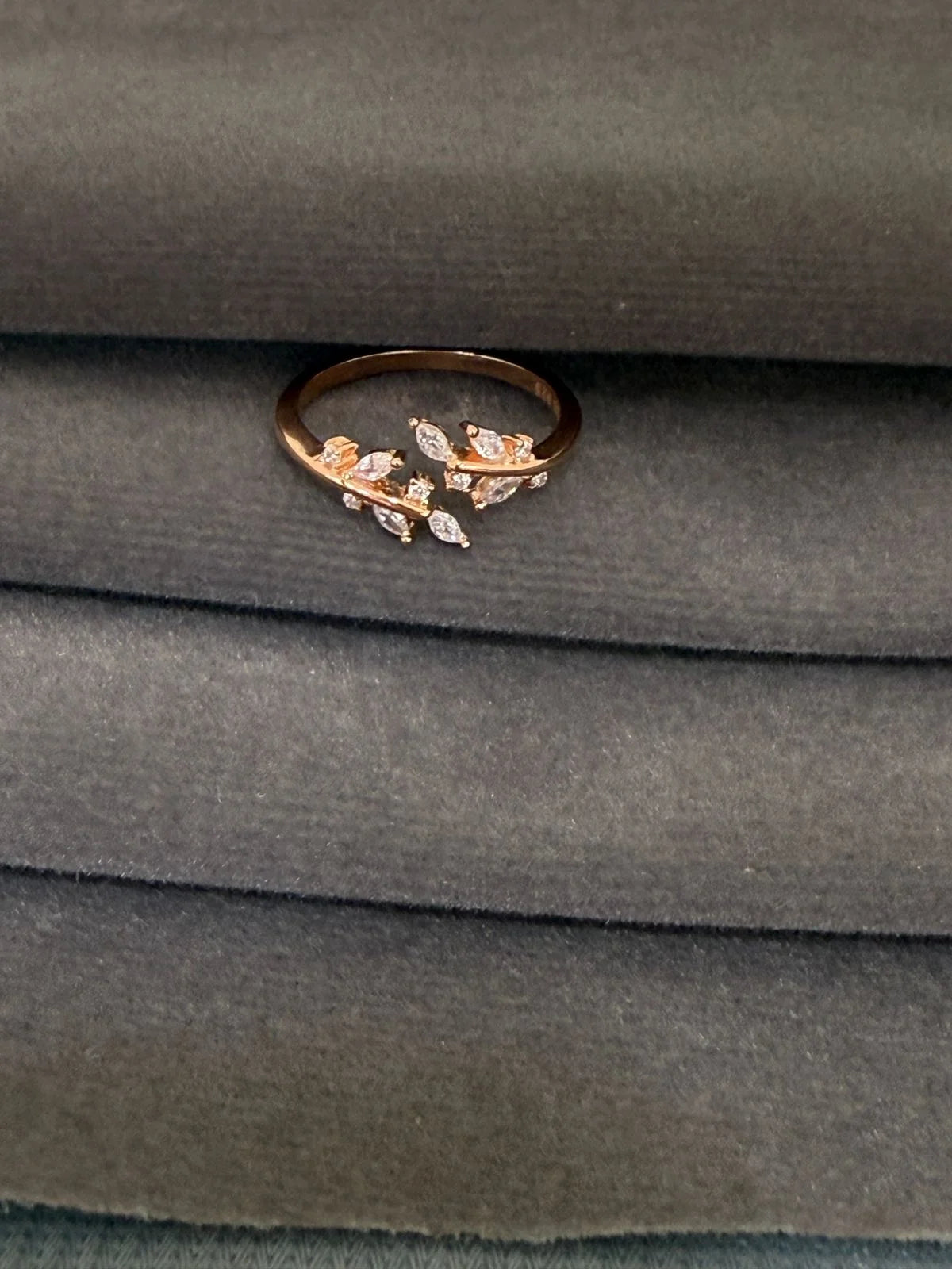 Rose gold ring with floral design on a gray fabric background