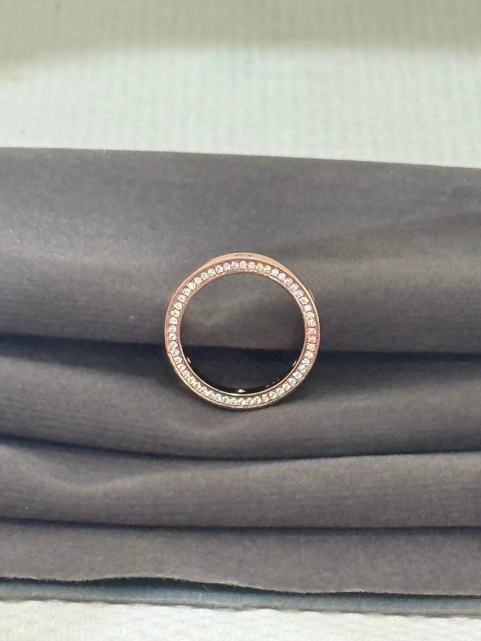 Rose gold ring with small stones on a gray fabric background