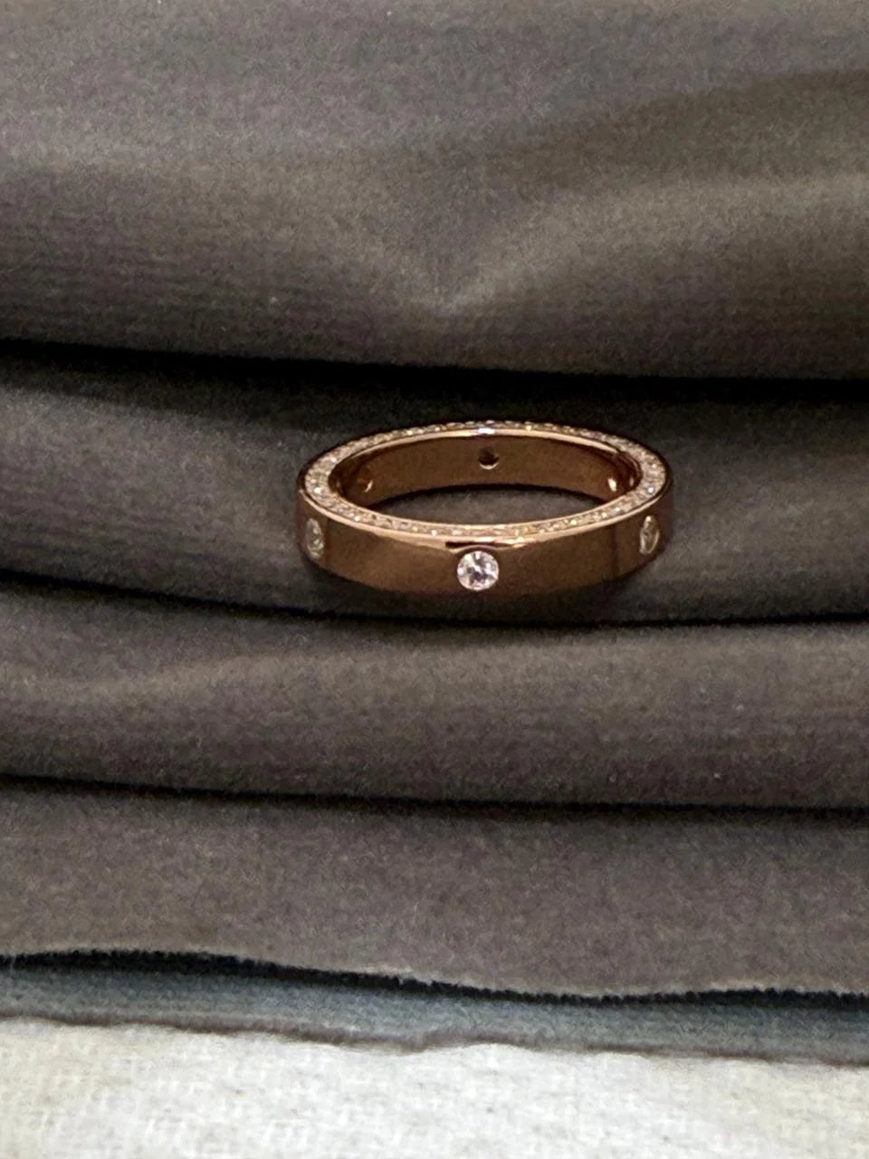 Rose gold ring with diamonds on gray fabric