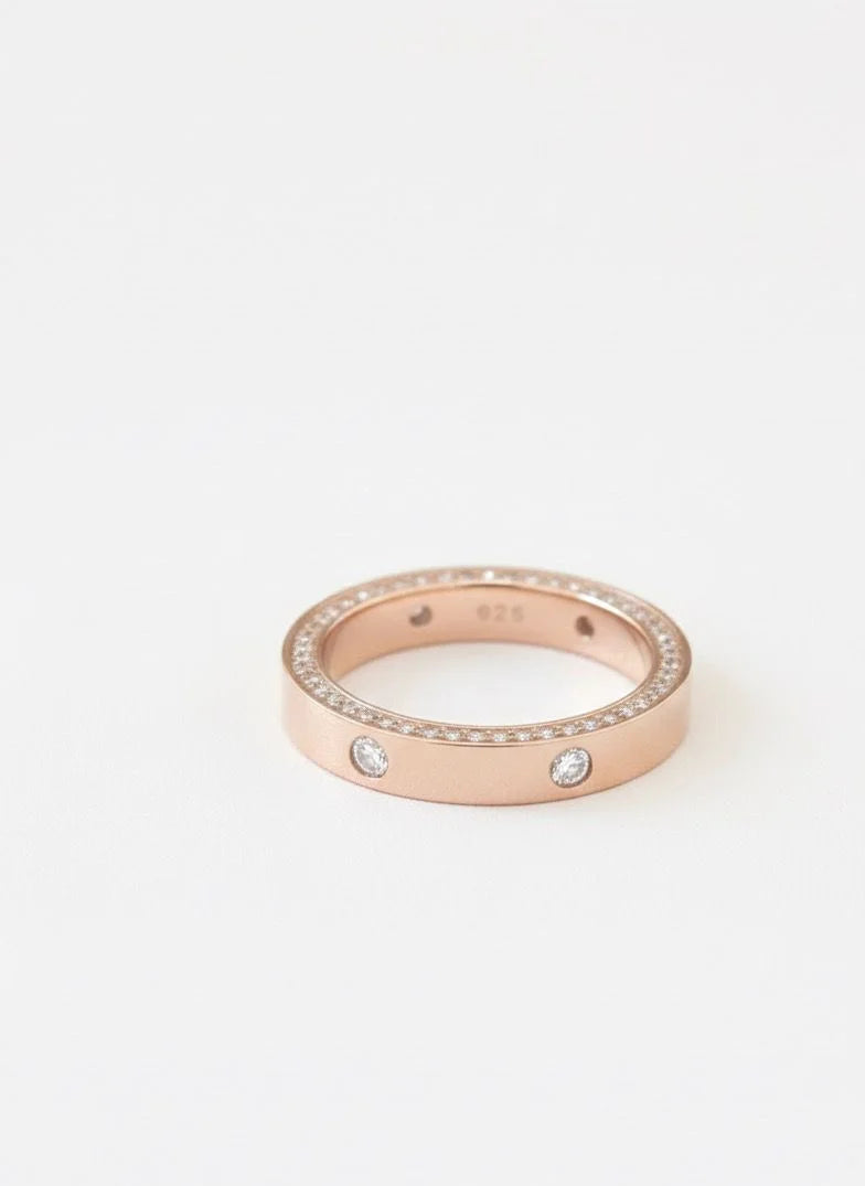 Rose gold ring with embedded diamonds on a white background