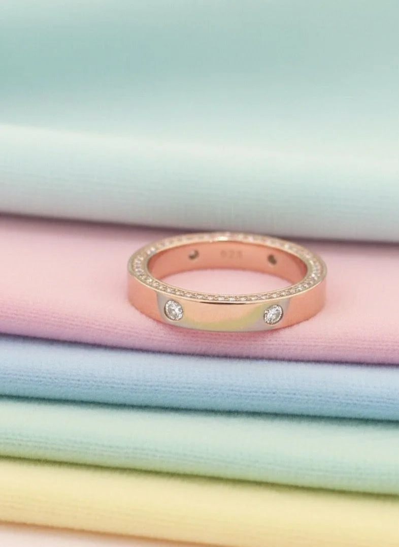Rose gold ring with small diamonds on pastel fabric background