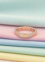 Rose gold ring with small diamonds on pastel fabric background