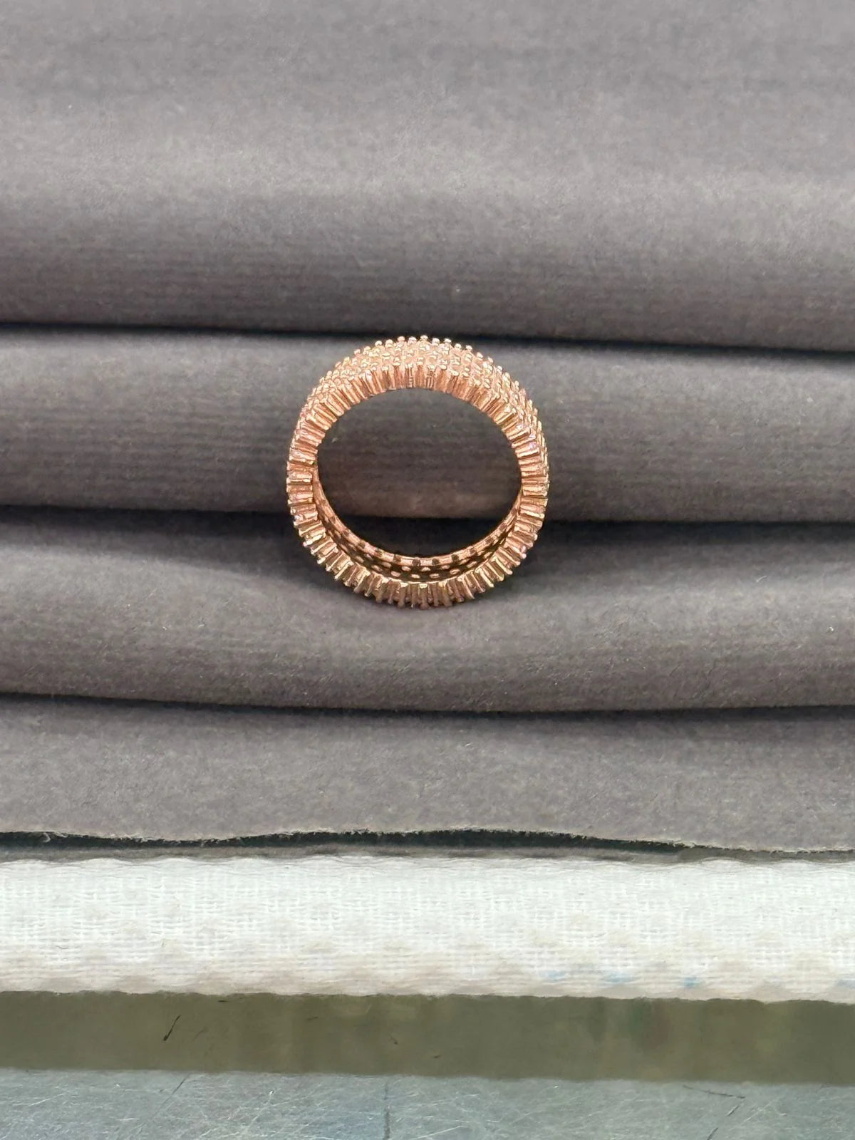 Rose gold ring on a stack of gray fabric