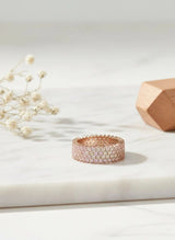 Rose gold ring with small stones on a light surface with decorative elements