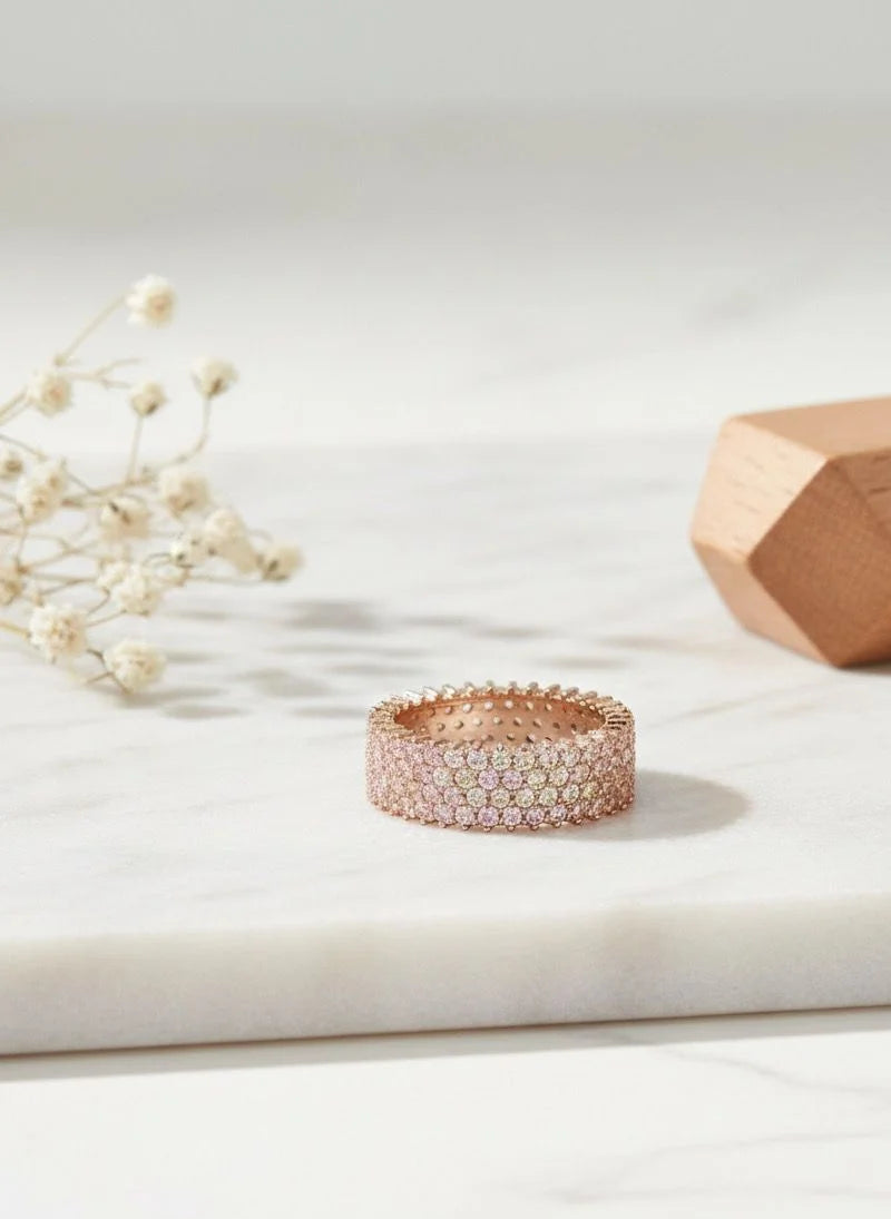 Rose gold ring with small stones on a light surface with decorative elements
